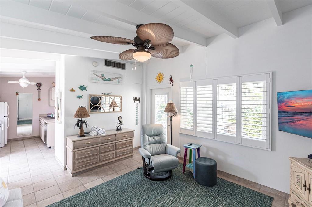 A living room with a ceiling fan, light blue recliner, and white plantation shutters — 6006 MIDNIGHT PASS ROAD UNIT 68, SARASOTA, FL