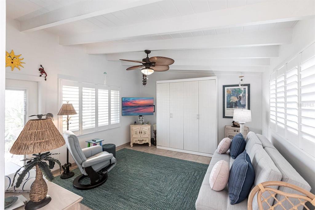 A living room features a white ceiling with exposed beams, a ceiling fan, and shutters — 6006 MIDNIGHT PASS ROAD UNIT 68, SARASOTA, FL