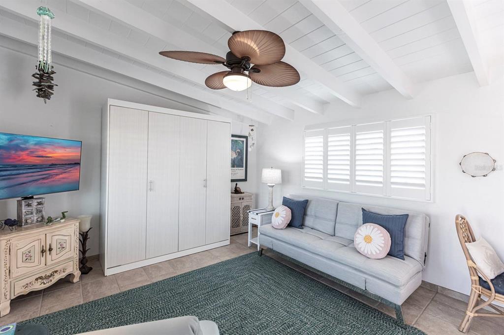A living room features a white wardrobe, a gray sofa, and a ceiling fan — 6006 MIDNIGHT PASS ROAD UNIT 68, SARASOTA, FL