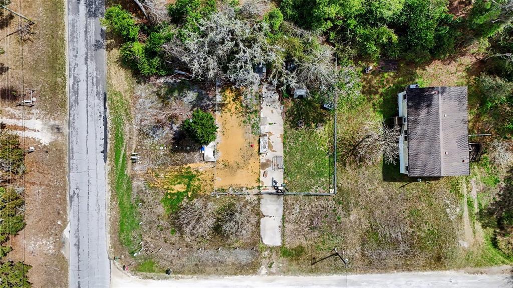 An aerial view shows a house, a concrete driveway, and a fenced yard with trees — 34884 REYNOLDS STREET, DADE CITY, FL