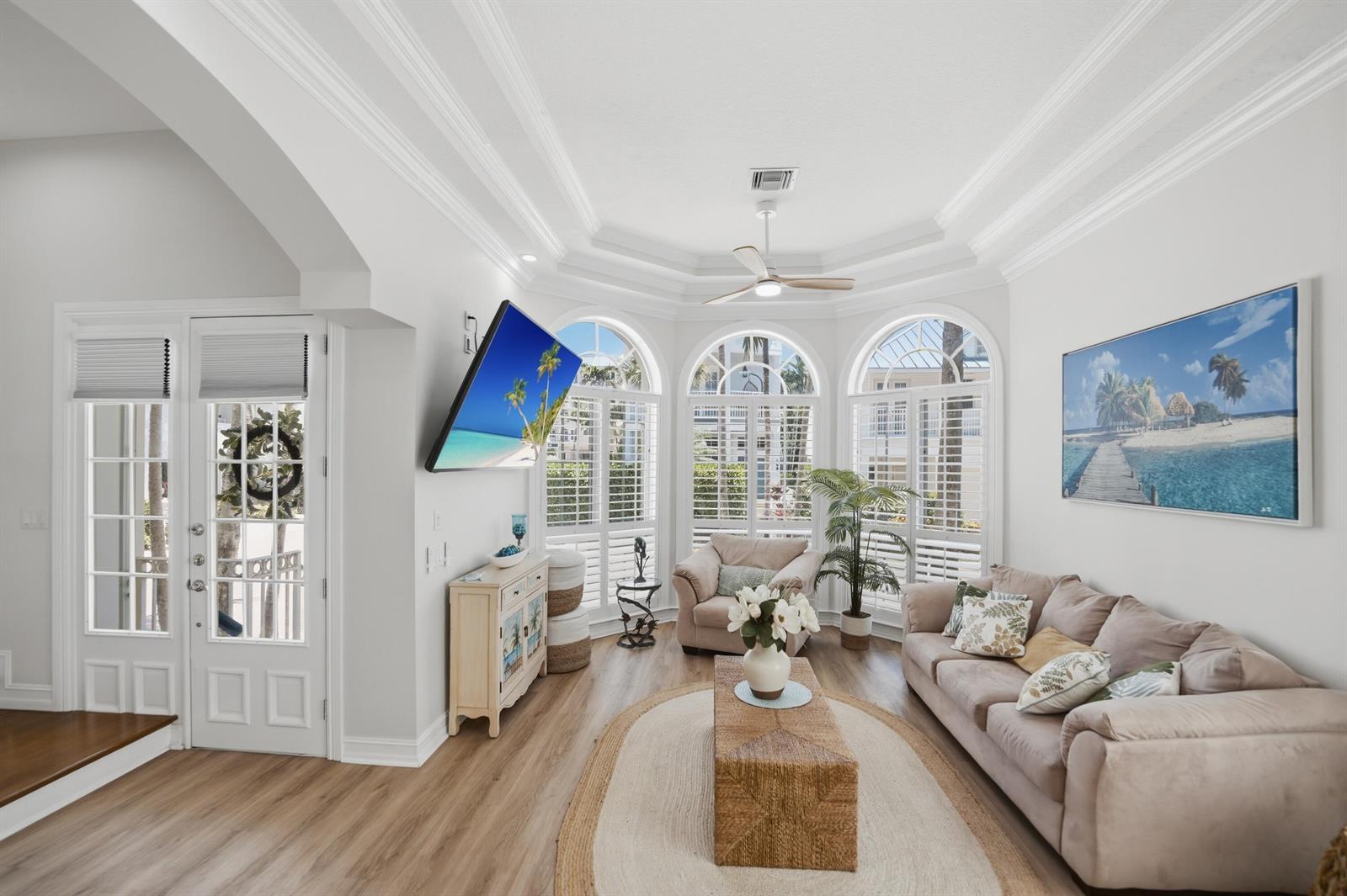 A bright living room features a beige sofa, a central coffee table, and arched windows — 149 Key Lane, Jupiter FL 33477, JUPITER, FL