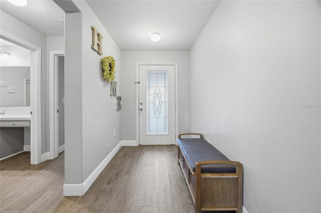 An entryway features light gray walls, wood-look flooring, a wooden bench, and a front door — 6461 DOMENICO COURT, GROVELAND, FL