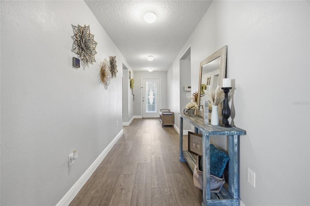 A hallway with wood-look tile flooring, light gray walls, and a rustic console table — 6461 DOMENICO COURT, GROVELAND, FL