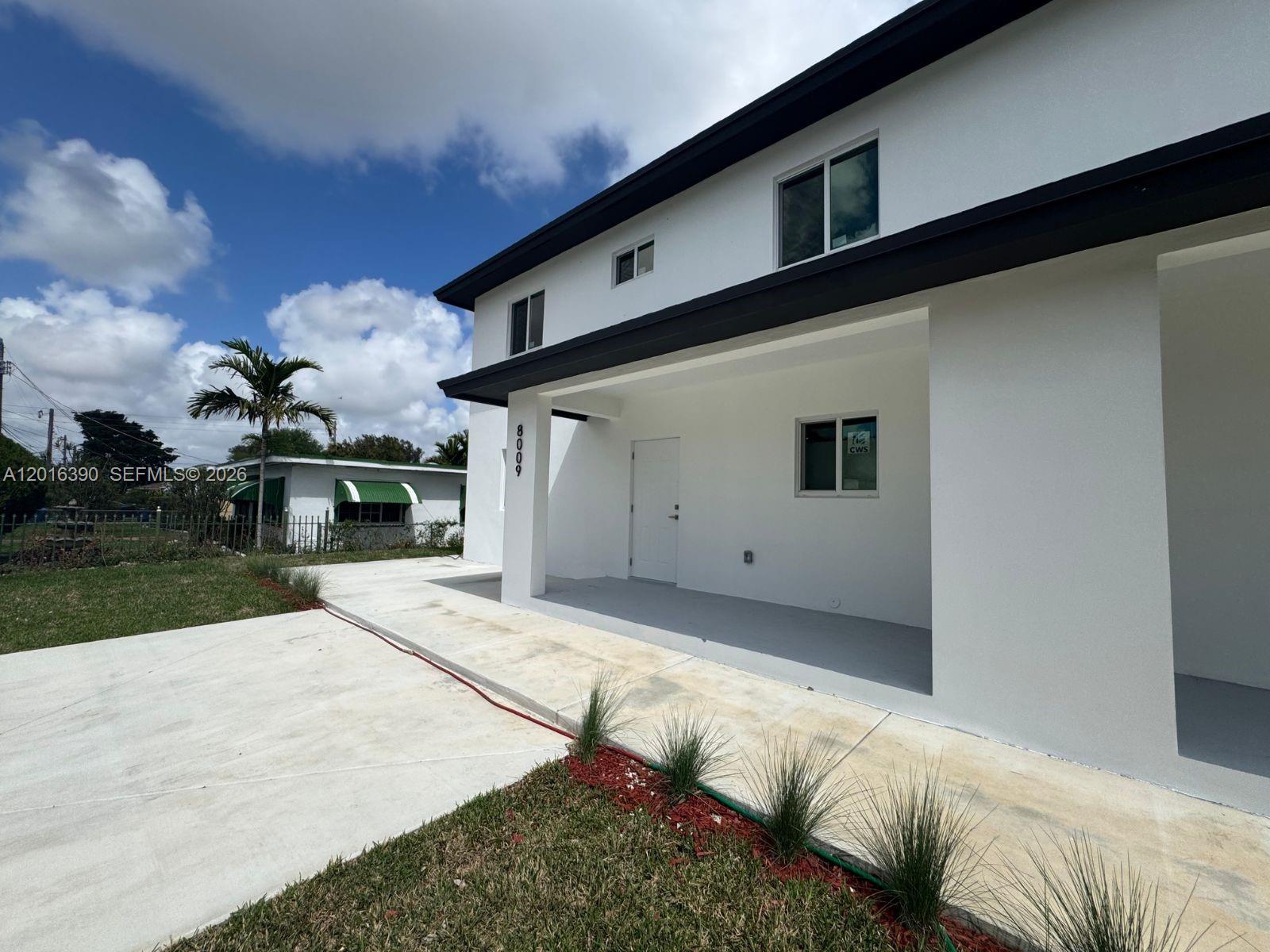 A white two-story building features a covered entrance, a concrete driveway, and small landscaping — 8005 NW 14th ct # 8005, Miami FL 33147, MIAMI, FL