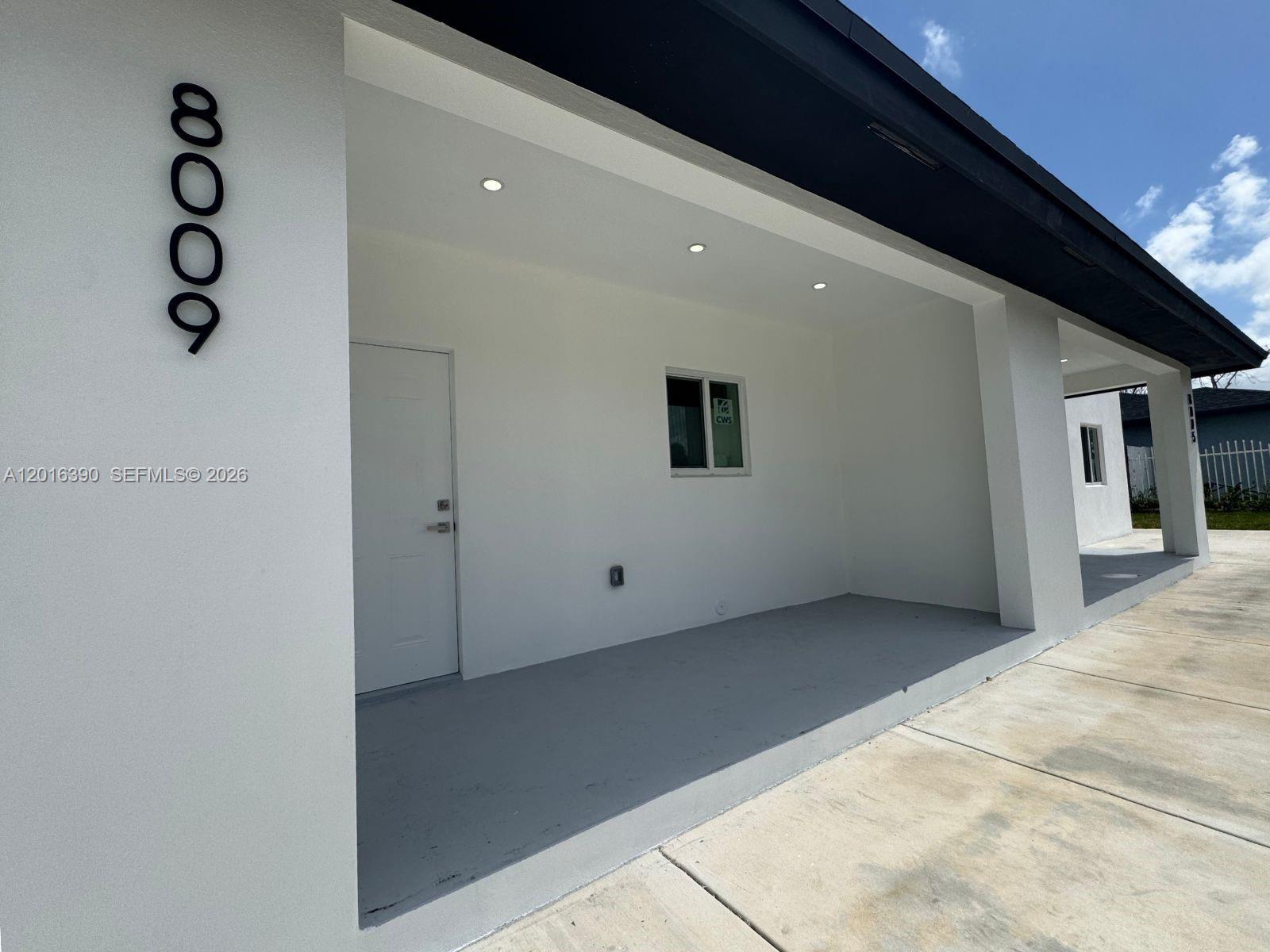 A white exterior wall features a vertical address number, a door, and a covered porch — 8005 NW 14th ct # 8005, Miami FL 33147, MIAMI, FL