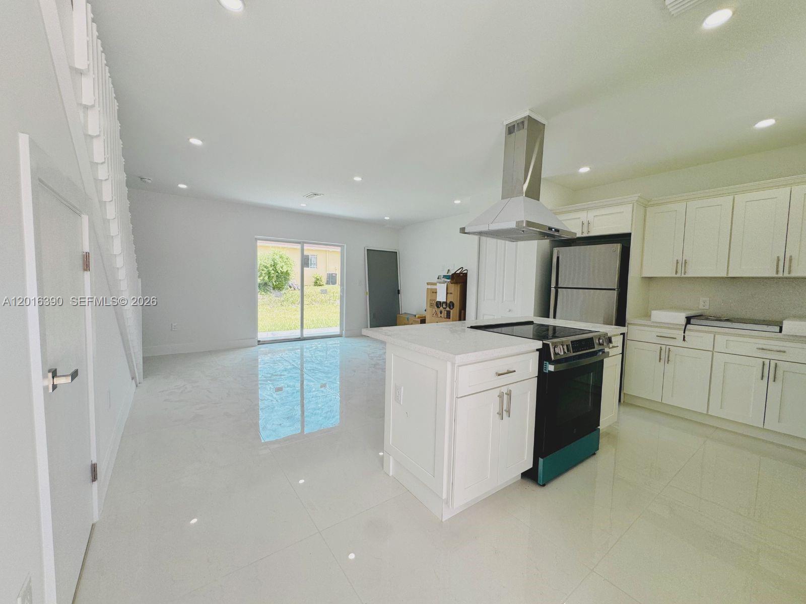 A modern kitchen with white cabinets and a central island opens into a living area — 8005 NW 14th ct # 8005, Miami FL 33147, MIAMI, FL