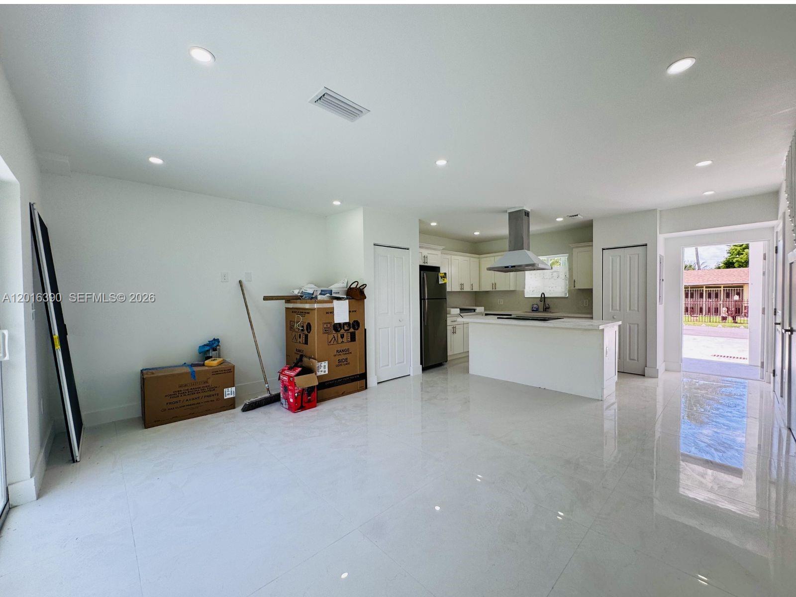 A bright, open-concept kitchen features white cabinetry, a central island, and polished tile flooring — 8005 NW 14th ct # 8005, Miami FL 33147, MIAMI, FL