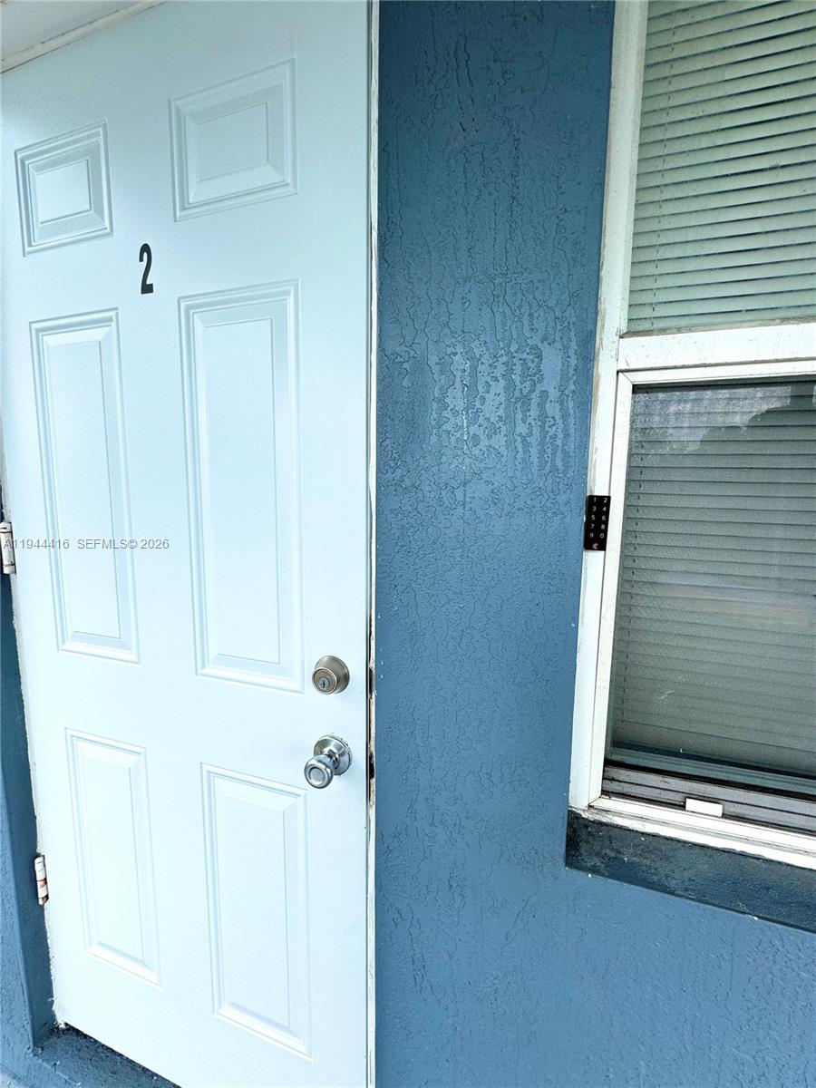 A light blue door with the number two is next to a window with blinds — 1821 NW 33rd  St, Miami FL 33142, MIAMI, FL