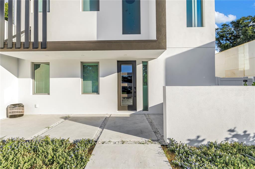The exterior of a modern white house features a front door, windows, and concrete walkway — 2305 TEMPLE STREET, SARASOTA, FL