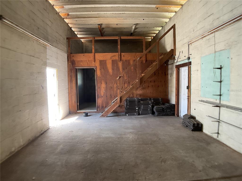 An industrial-style room features concrete walls, a wooden loft with stairs, and a concrete floor — 4460 SW HIGHWAY 17, ARCADIA, FL