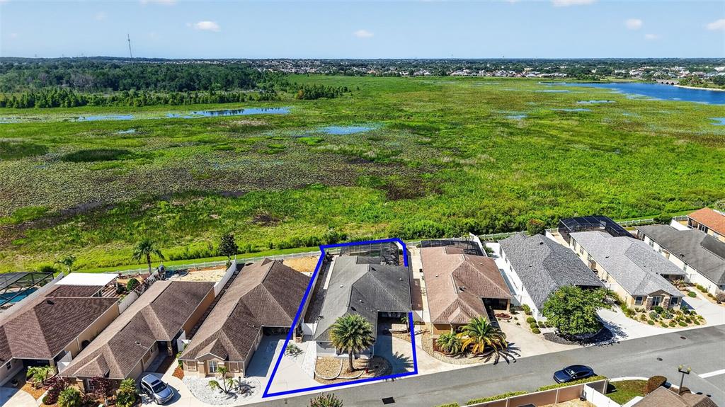 An aerial view shows a suburban house with a blue outline in a residential neighborhood — 562 AVECILLA DRIVE, THE VILLAGES, FL