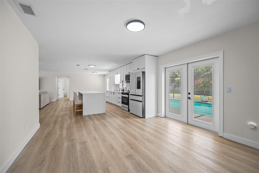 A modern kitchen with white cabinetry and an island opens to a pool area — 2911 GRAYTON STREET, DELTONA, FL
