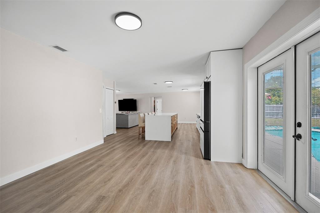 A bright, open-concept kitchen and living area features light wood-look flooring and a kitchen island — 2911 GRAYTON STREET, DELTONA, FL