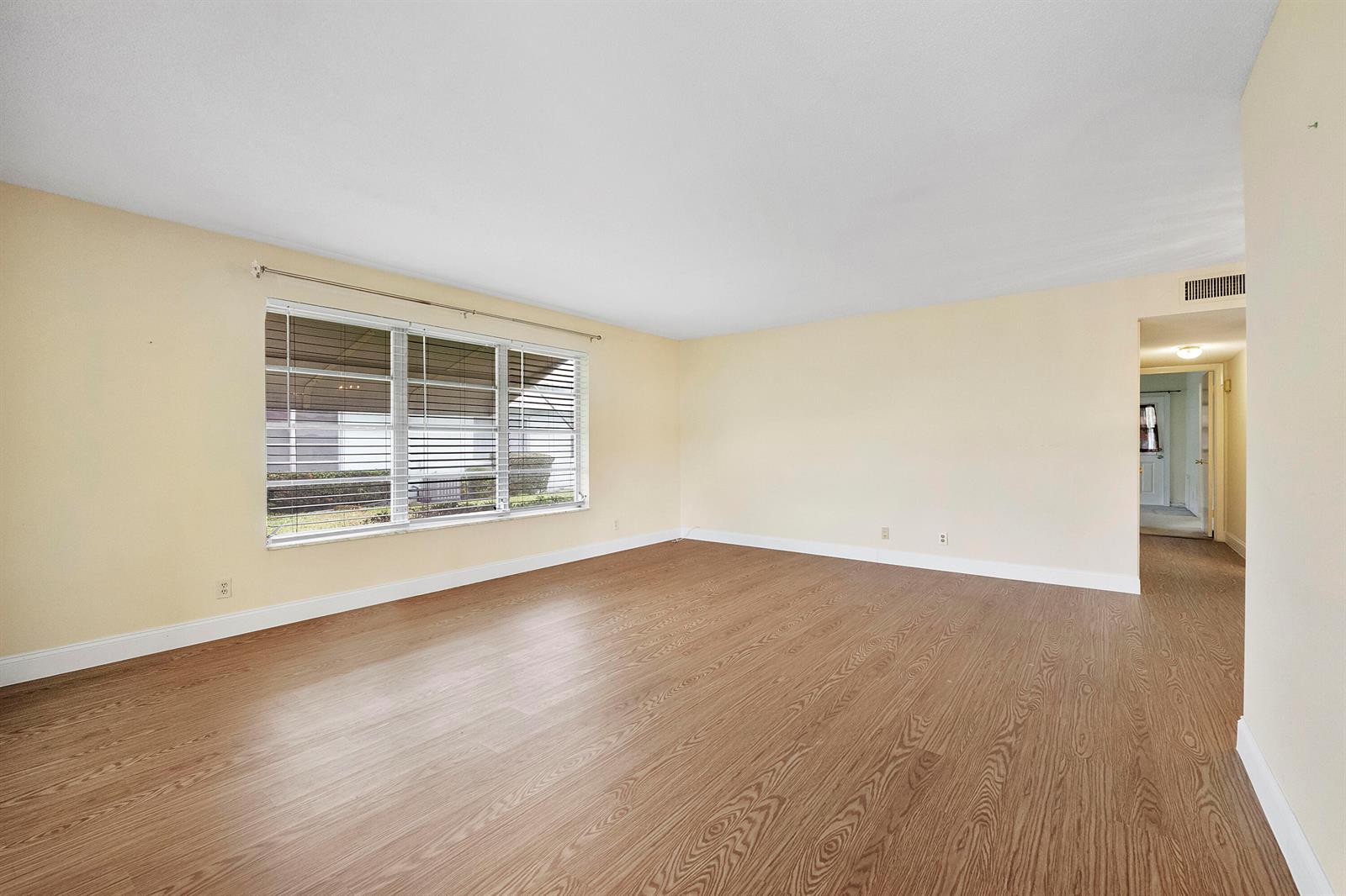 An empty room with light-colored walls, wood-look flooring, and a large window with blinds — 212 High Point Terrace W # A, Delray Beach FL 33445, DELRAY BEACH, FL