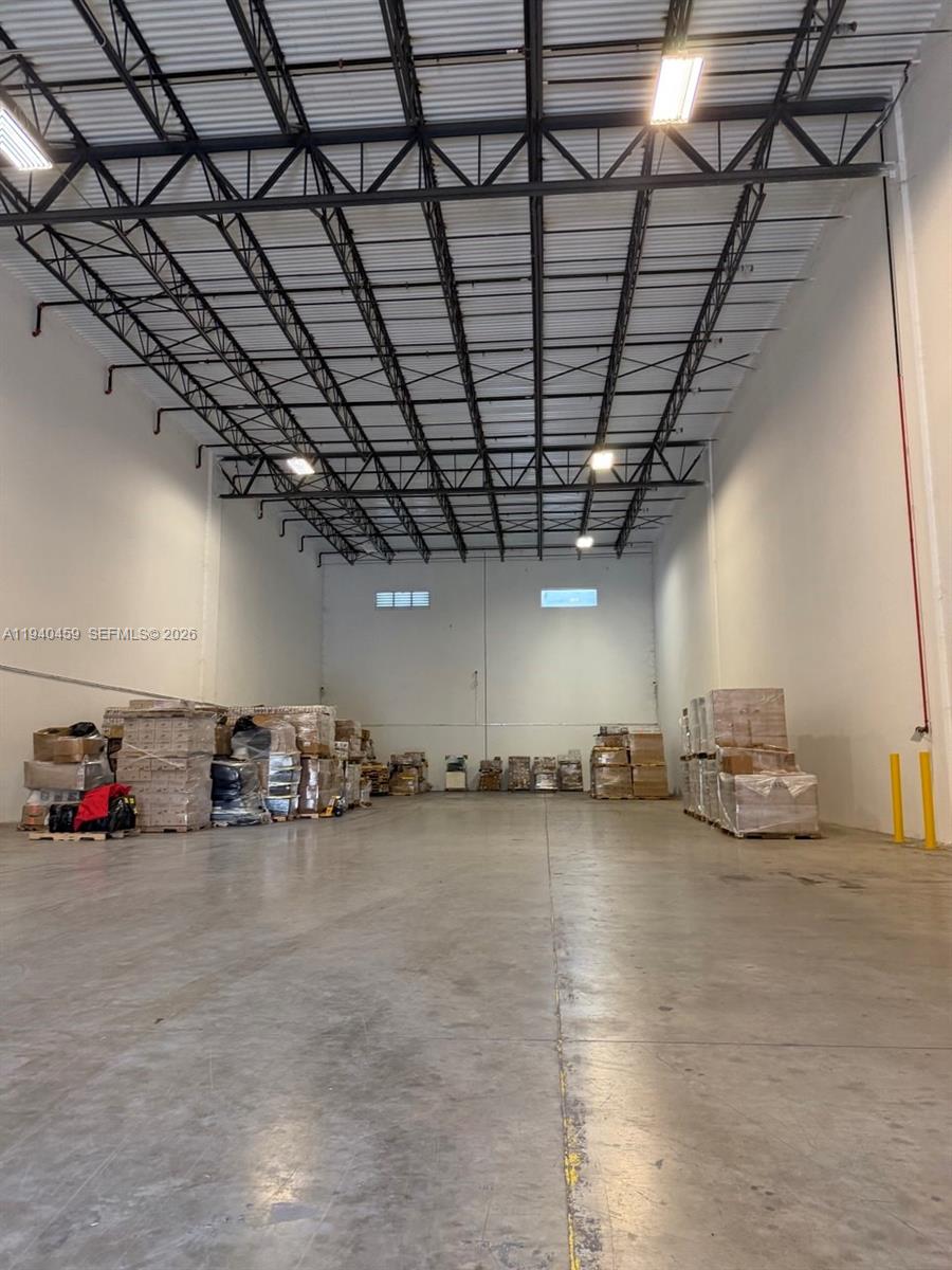 A large, empty warehouse space features high ceilings with exposed metal trusses and concrete floors — 14001 NW 112th Ave, Hialeah Gardens FL 33018, HIALEAH GARDENS, FL
