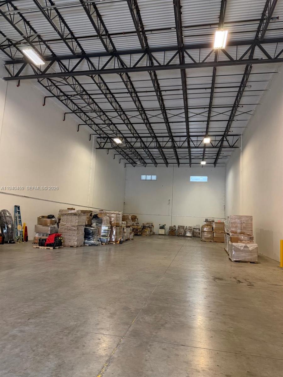 An interior view of a large, high-ceilinged warehouse space with concrete floors and palletized inventory — 14001 NW 112th Ave, Hialeah Gardens FL 33018, HIALEAH GARDENS, FL