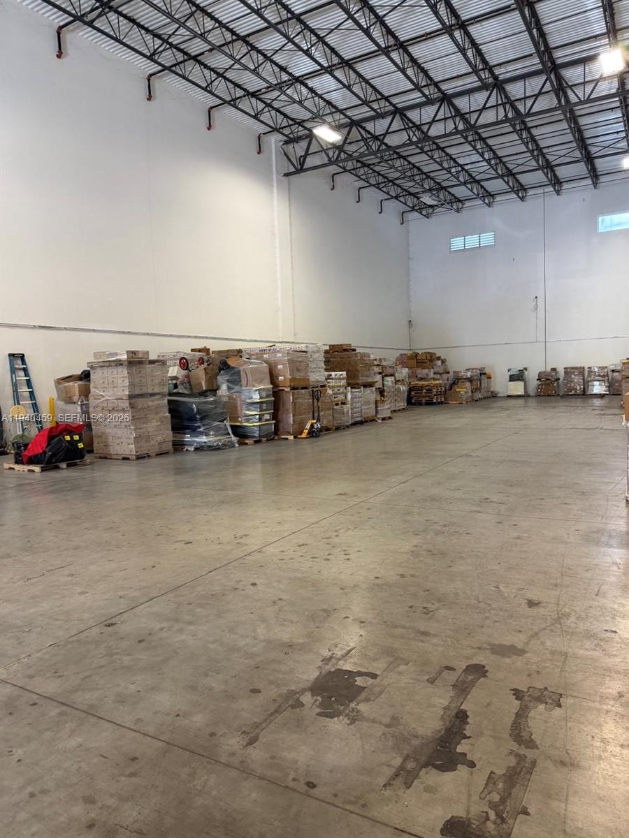A spacious warehouse interior features a concrete floor, high ceilings, and stacked shipping pallets — 14001 NW 112th Ave, Hialeah Gardens FL 33018, HIALEAH GARDENS, FL