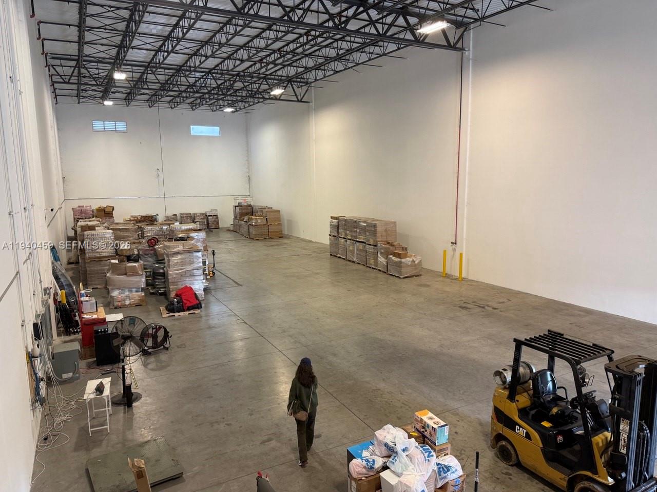A high-ceiling warehouse features concrete floors, palletized inventory, and a yellow forklift — 14001 NW 112th Ave, Hialeah Gardens FL 33018, HIALEAH GARDENS, FL