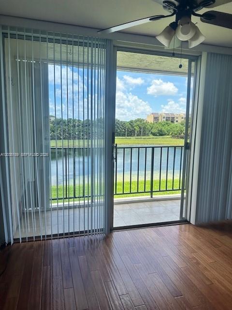 A room with wood flooring and a ceiling fan overlooks a balcony and a lake — 870 NW 87th Ave # 302, Miami FL 33172, MIAMI, FL