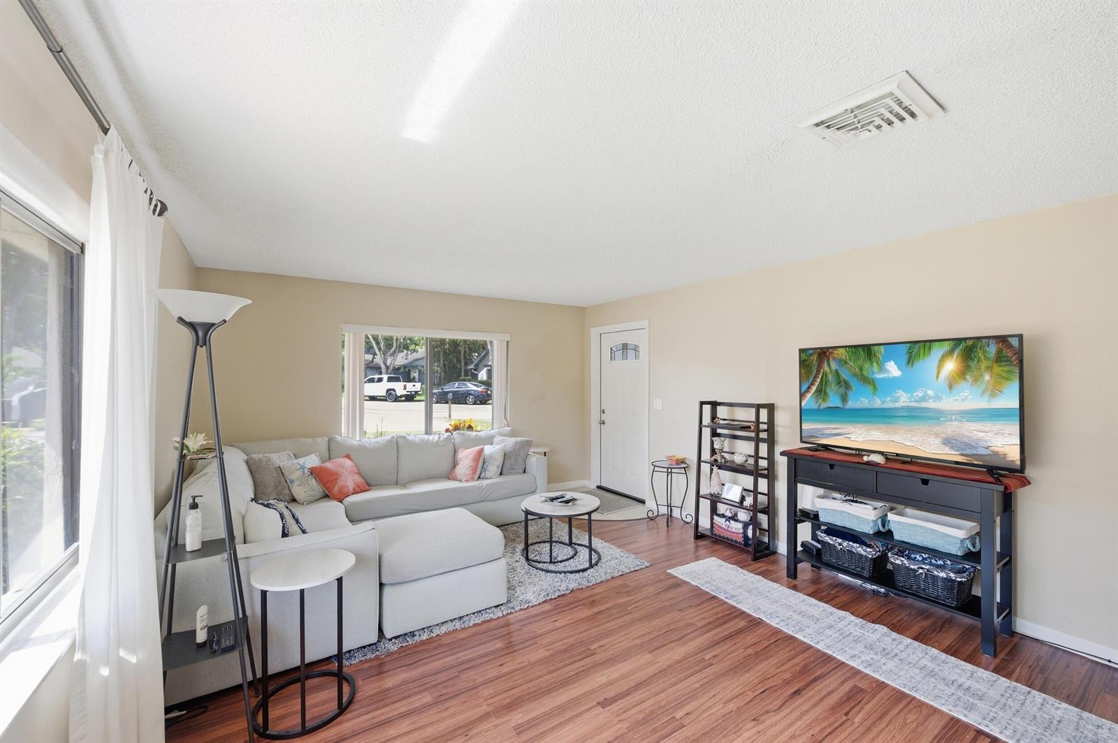 A living room features a sectional sofa, a television on a stand, and wood flooring — 10222 Pine Drive, Boynton Beach FL 33437, BOYNTON BEACH, FL