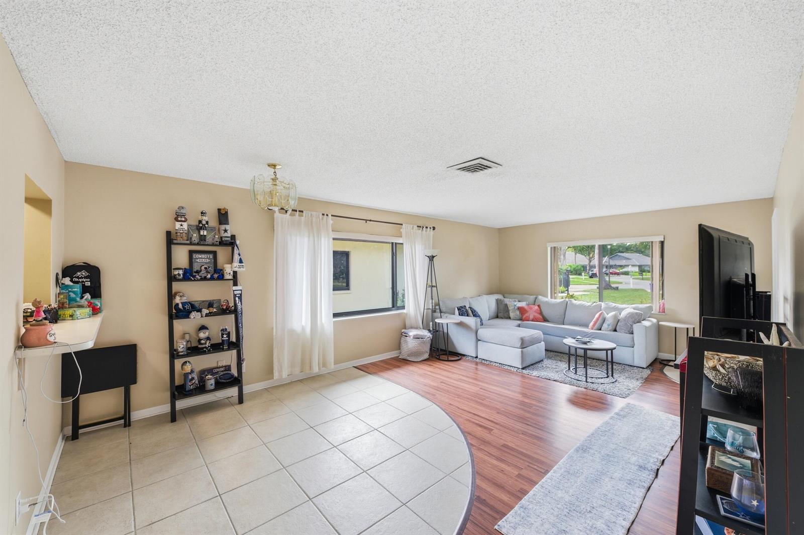 A living room features a tiled floor area, wood-look flooring, and a large sectional sofa — 10222 Pine Drive, Boynton Beach FL 33437, BOYNTON BEACH, FL