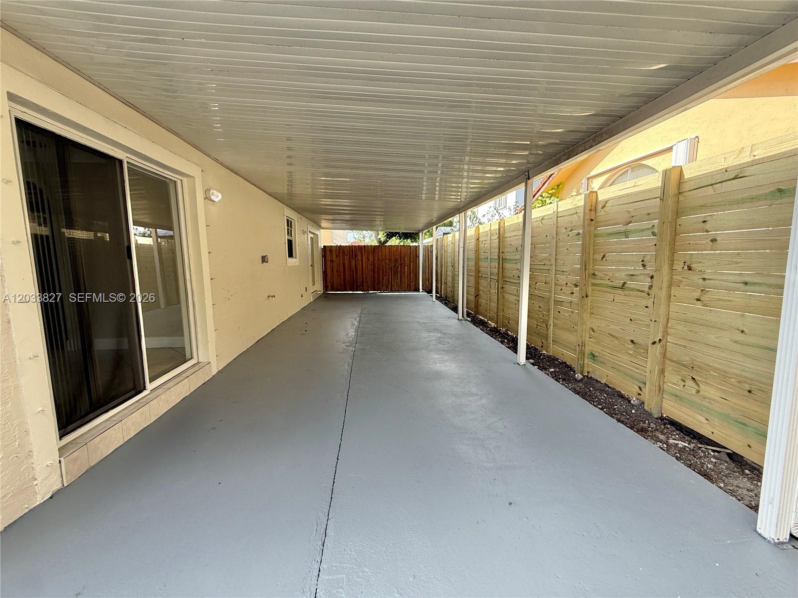 A covered concrete patio area features a sliding glass door and a wooden privacy fence — 9121 SW 215th Ter, Cutler Bay FL 33189, CUTLER BAY, FL
