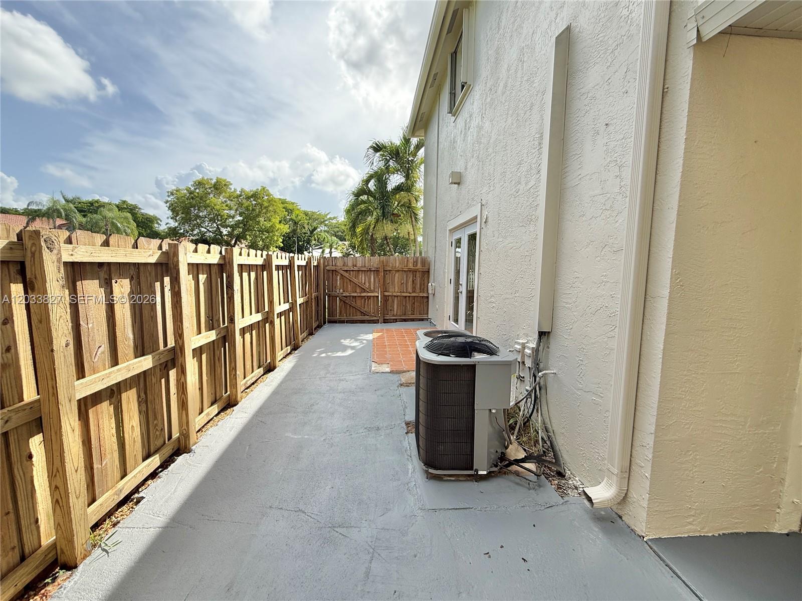 A side yard features a concrete patio, a wooden fence, and an outdoor air conditioning unit — 9121 SW 215th Ter, Cutler Bay FL 33189, CUTLER BAY, FL