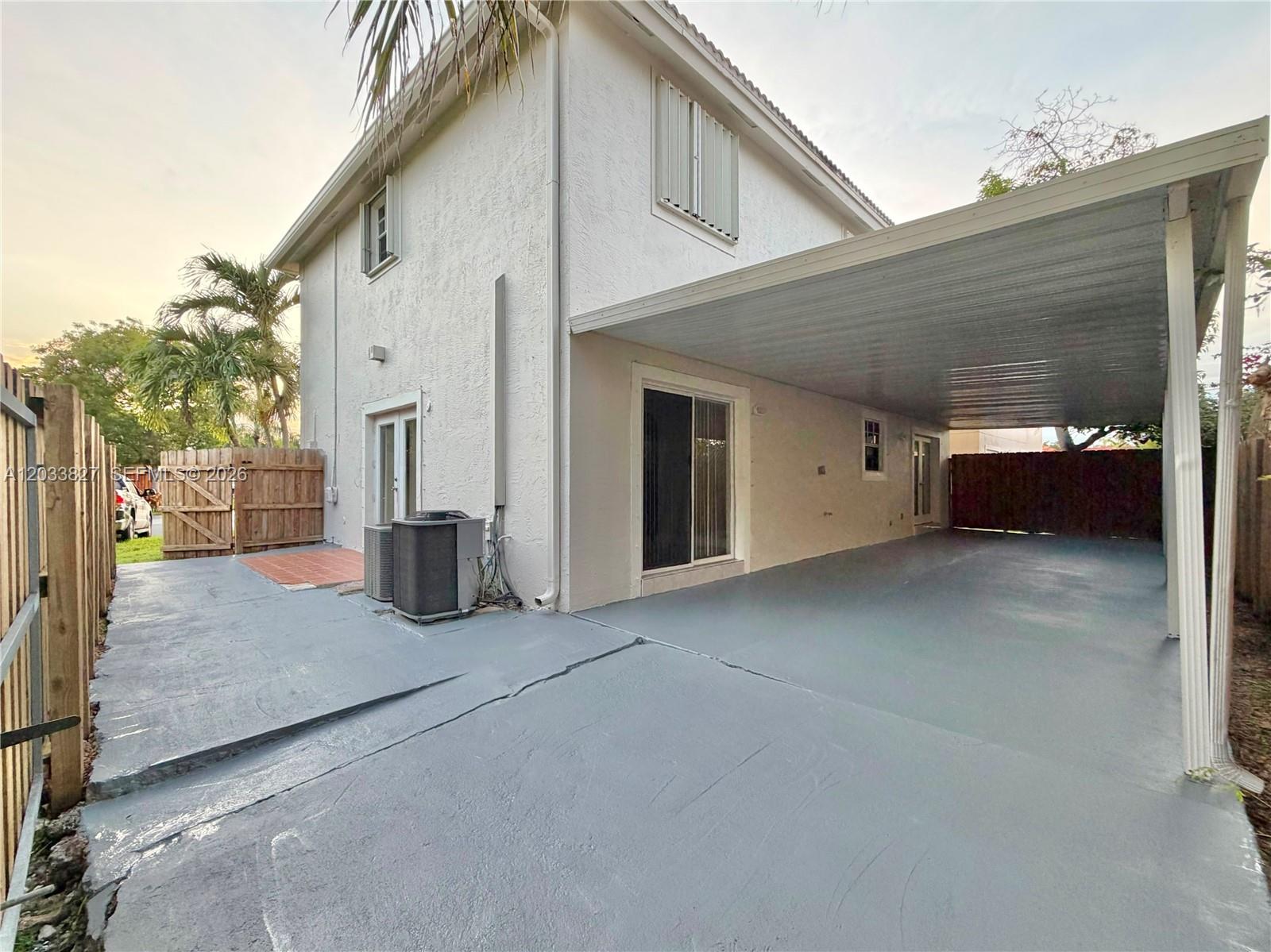 A two-story house exterior features a gray painted concrete patio and a covered carport — 9121 SW 215th Ter, Cutler Bay FL 33189, CUTLER BAY, FL
