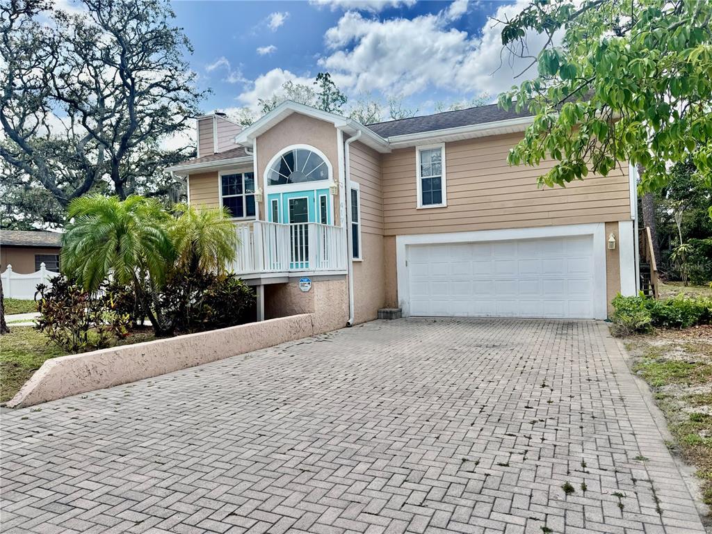 A two-story house with tan siding, a white garage door, and a paved driveway — 419 KENTUCKY AVENUE, CRYSTAL BEACH, FL