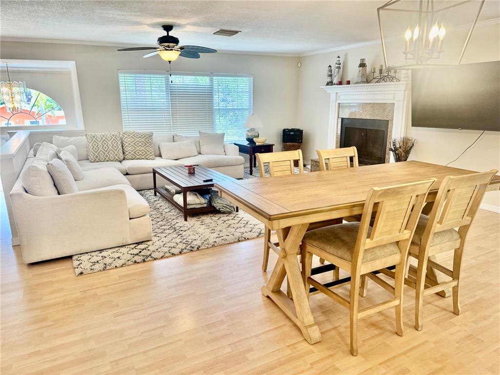 A living and dining room features light wood flooring, a sectional sofa, and a fireplace — 419 KENTUCKY AVENUE, CRYSTAL BEACH, FL