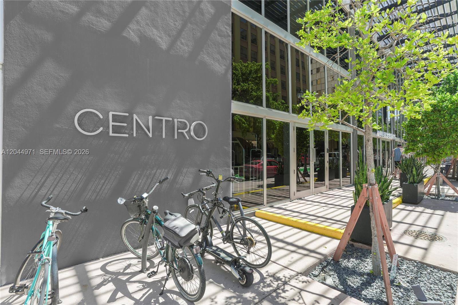 The exterior of a building labeled Centro features a gray wall, glass windows, and bicycles — 151 SE 1st St, Miami FL 33131, MIAMI, FL