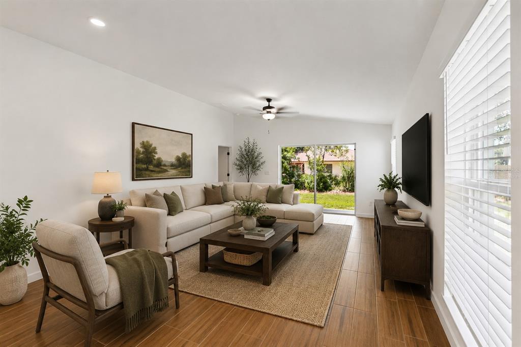 A living room features a sectional sofa, coffee table, television, and sliding glass doors — 614 BLACKTHORN DRIVE, LAKELAND, FL