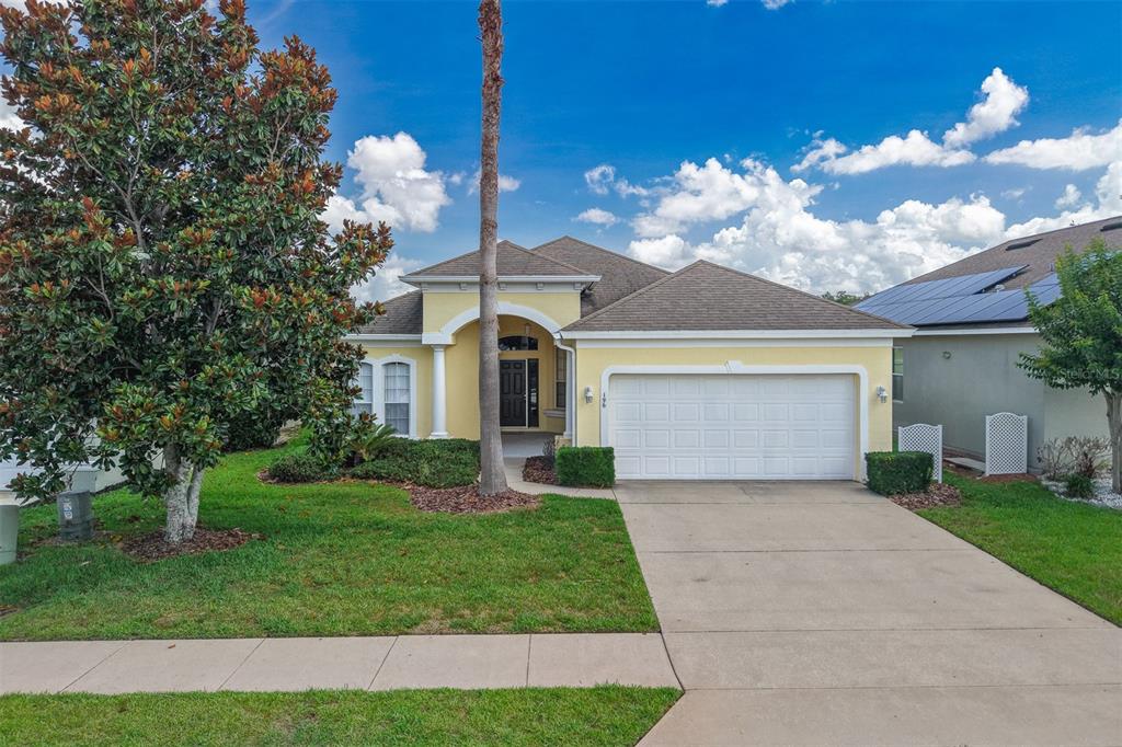 A yellow single-story house with a two-car garage, a palm tree, and a front lawn — 196 MINNIEHAHA CIRCLE, HAINES CITY, FL