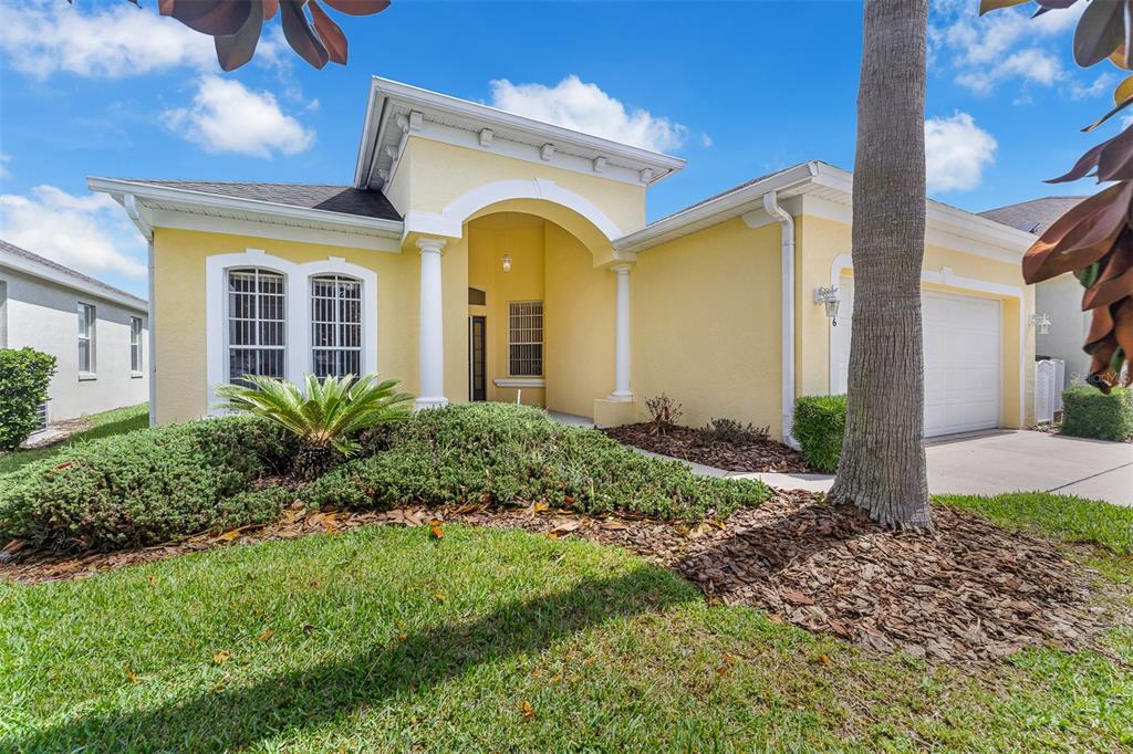 A yellow single-story house with a white arched entryway, columns, and a front-facing garage — 196 MINNIEHAHA CIRCLE, HAINES CITY, FL