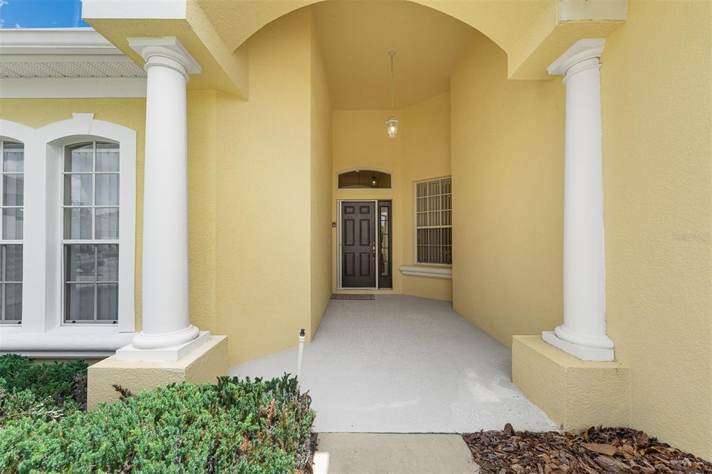 A covered entryway features two white columns, a dark front door, and yellow stucco walls — 196 MINNIEHAHA CIRCLE, HAINES CITY, FL