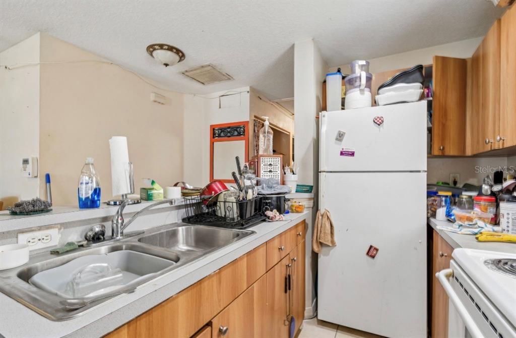 A kitchen features wood cabinets, a double-basin stainless steel sink, and a white refrigerator — 1901 E 32ND AVENUE, TAMPA, FL