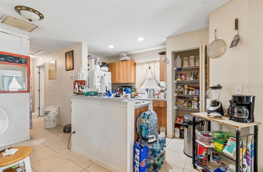A kitchen features a breakfast bar, wooden cabinets, a pantry, and a rolling utility cart — 1901 E 32ND AVENUE, TAMPA, FL