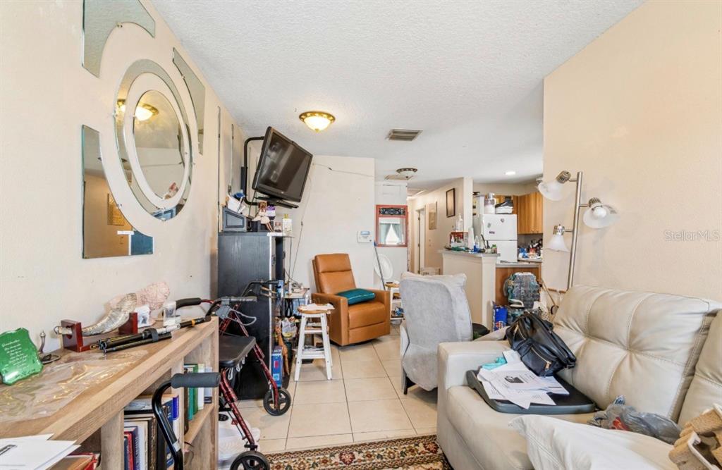 A living room with tile flooring, a beige sofa, a recliner, and a wall-mounted television — 1901 E 32ND AVENUE, TAMPA, FL