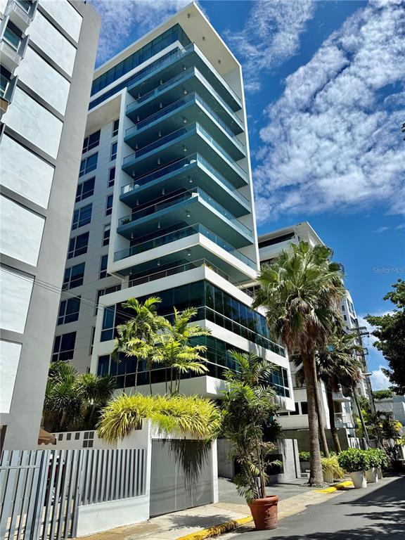 A modern multi-story apartment building features glass balconies and palm trees in the foreground — 7 C. MANUEL RODRIGUEZ SERRA UNIT 9, SAN JUAN, PR