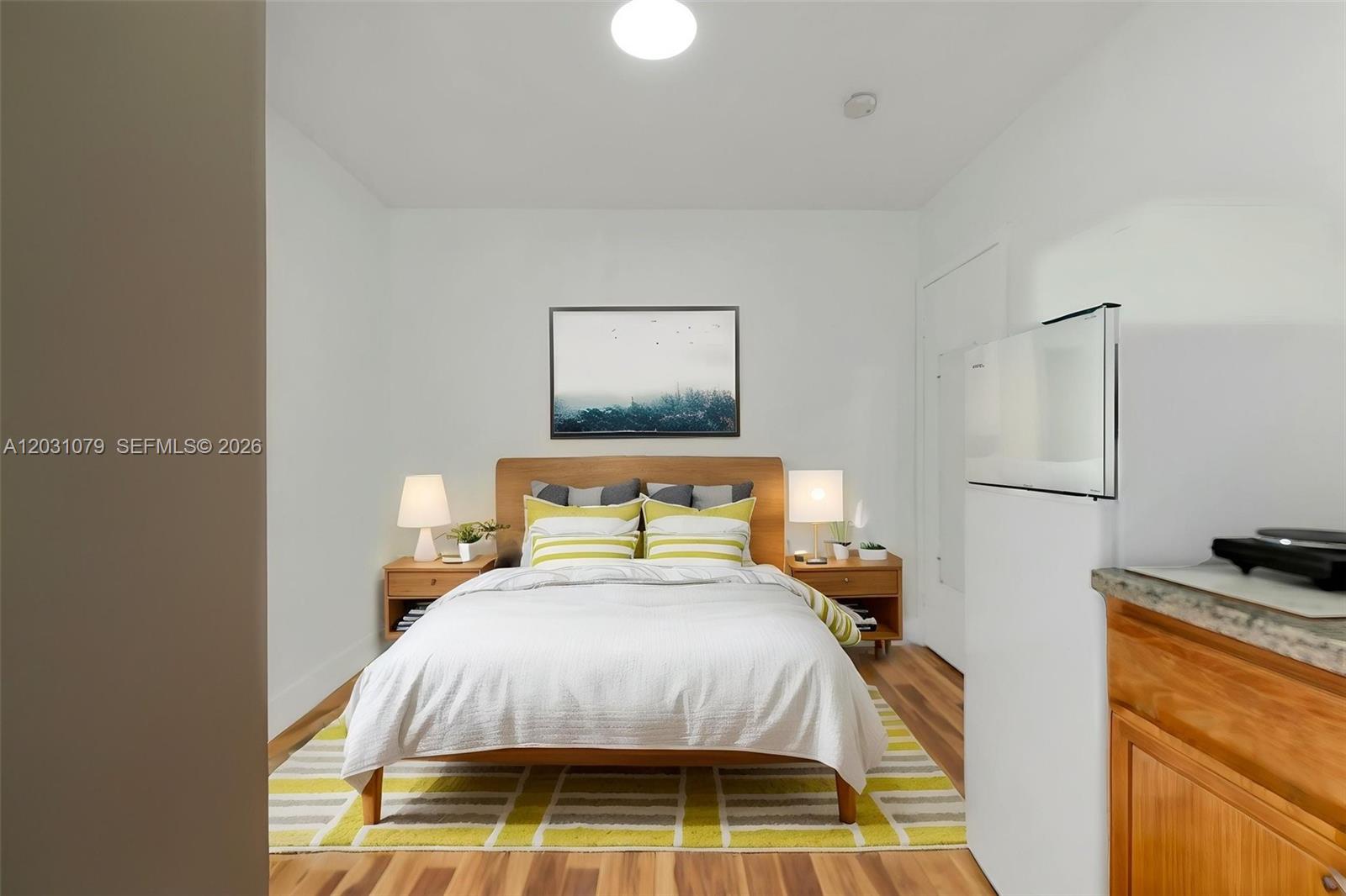 A bedroom features a wooden bed frame, two nightstands, and a yellow-patterned area rug — 6101 SW 24th St # 3, Miramar FL 33023, MIRAMAR, FL