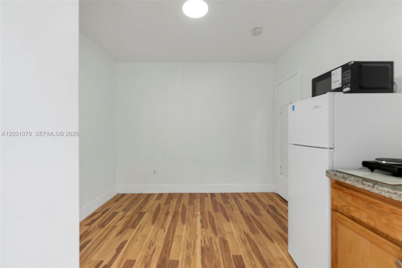 A small kitchen area features white walls, wood-look flooring, and a white refrigerator — 6101 SW 24th St # 3, Miramar FL 33023, MIRAMAR, FL