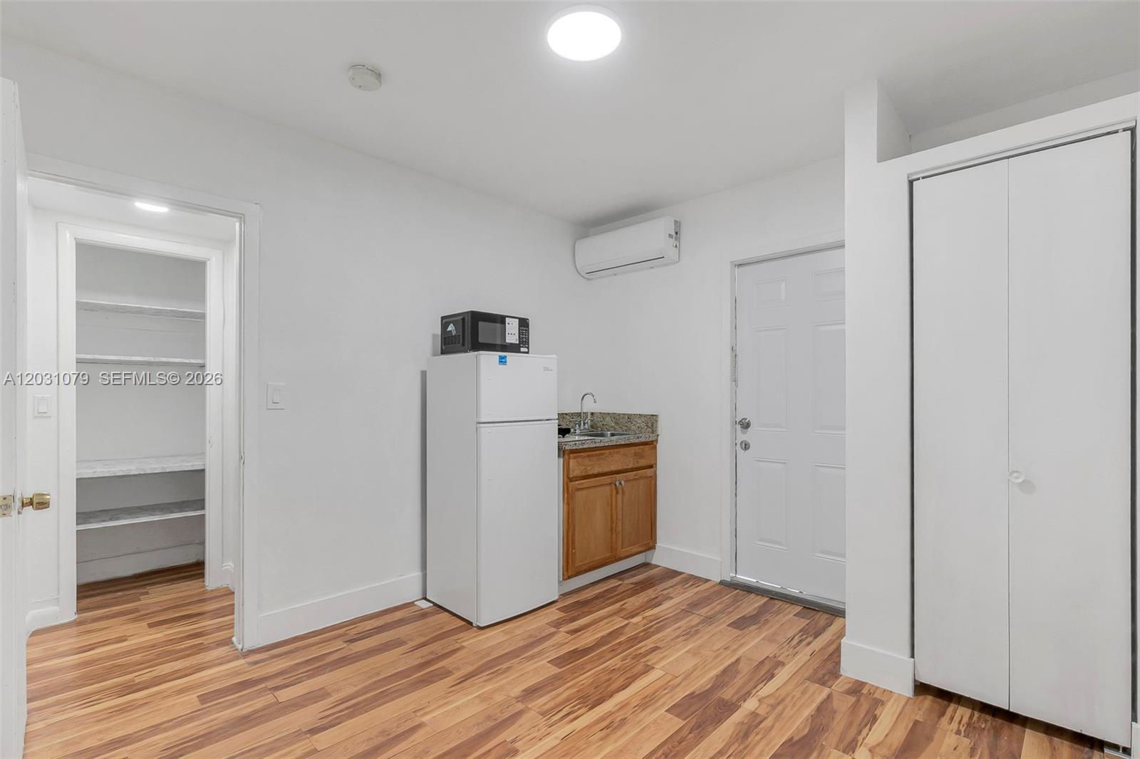 A small kitchenette with a refrigerator, sink, and microwave sits in a room with wood-look flooring — 6101 SW 24th St # 3, Miramar FL 33023, MIRAMAR, FL