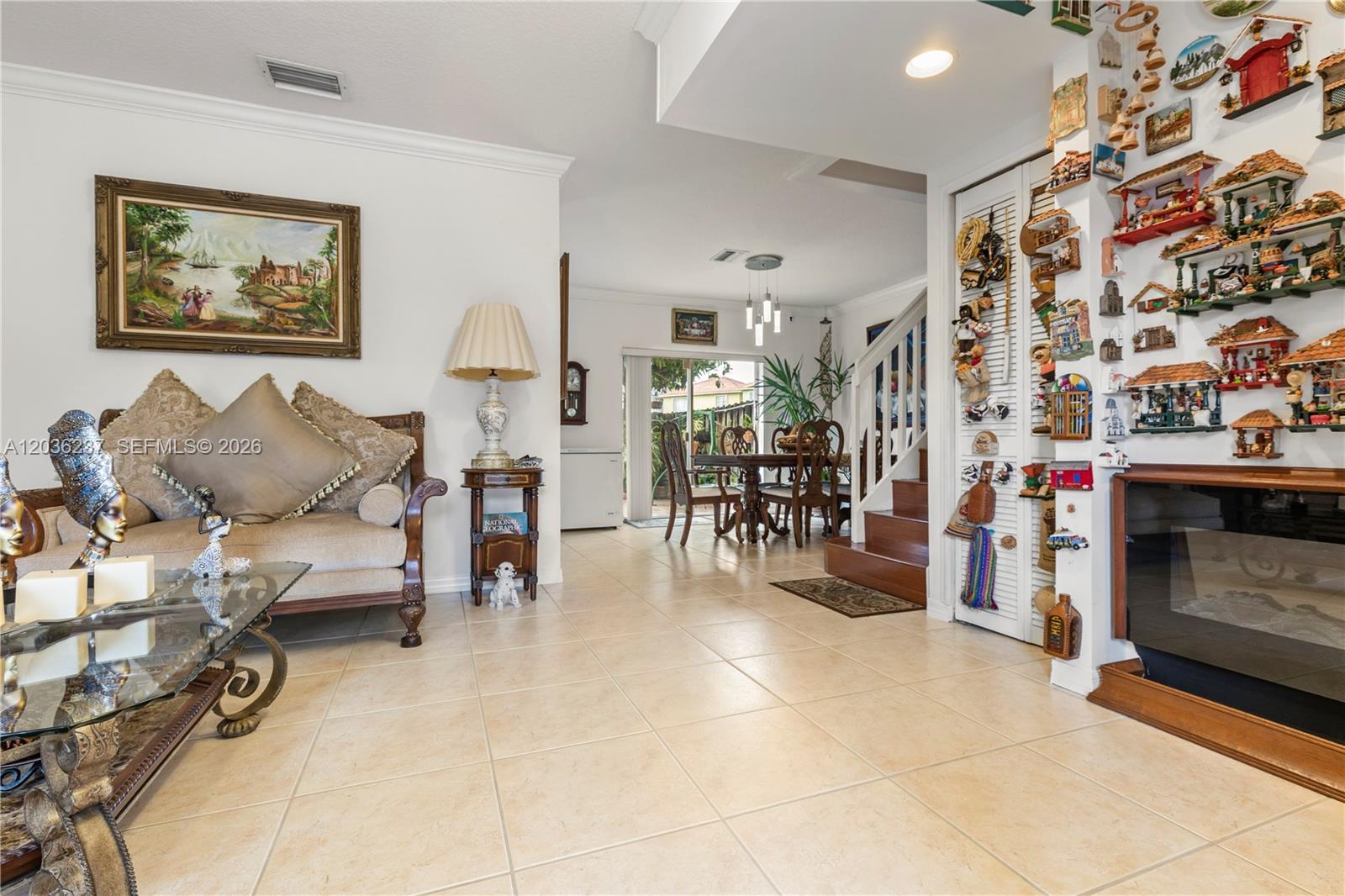 A living room with tile floors, a sofa, and a wall decorated with small ornaments — 13364 SW 143rd St, Miami FL 33186, MIAMI, FL