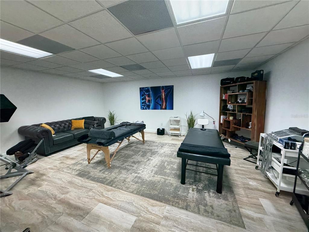 A therapy room features two massage tables, a dark leather sofa, and wood-look tile flooring — 828 LAKE BALDWIN LANE, ORLANDO, FL