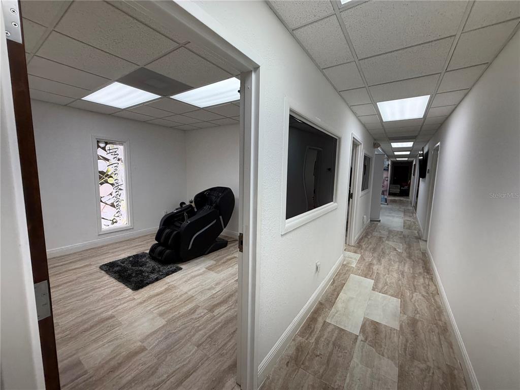 A hallway leads to a room containing a massage chair on a small rug — 828 LAKE BALDWIN LANE, ORLANDO, FL