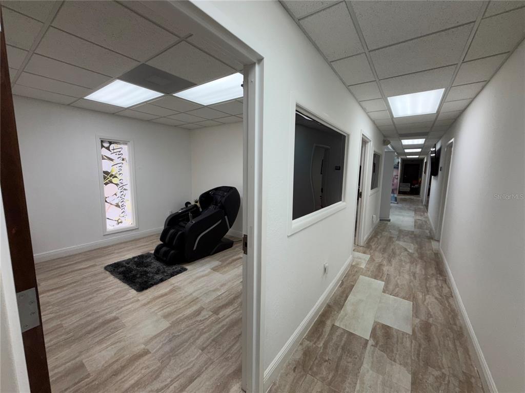 A hallway leads to a room containing a massage chair on a small rug — 828 LAKE BALDWIN LANE, ORLANDO, FL