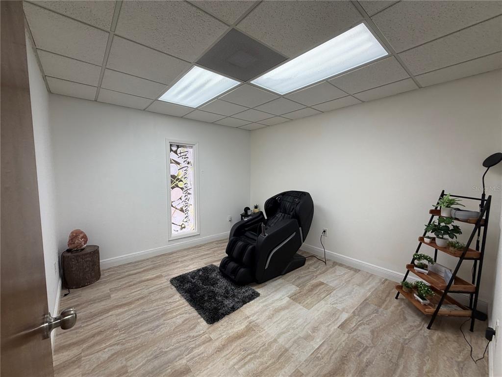 A room with wood-look tile flooring, a massage chair, a small shelf, and a window — 828 LAKE BALDWIN LANE, ORLANDO, FL