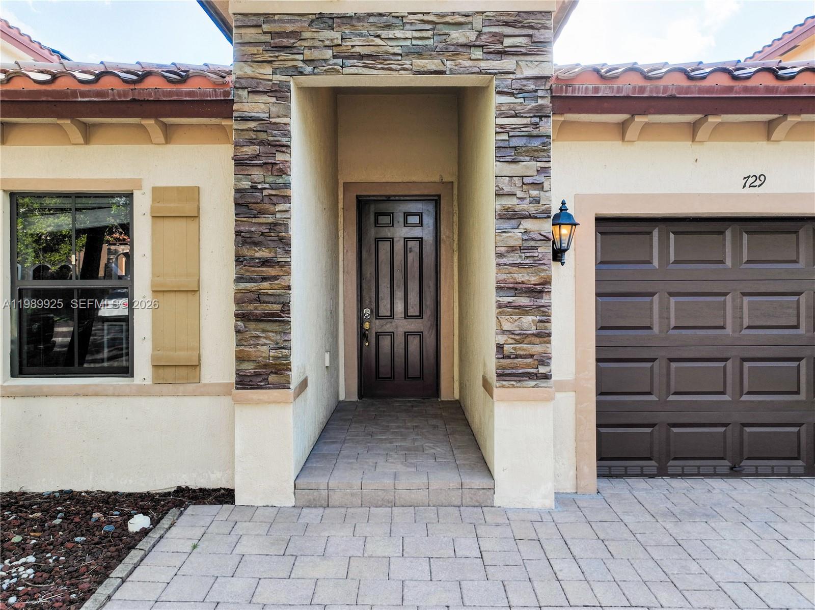 The exterior view shows a front entrance with a stone facade and a garage door — 729 SE 34th Ave, Homestead FL 33033, HOMESTEAD, FL