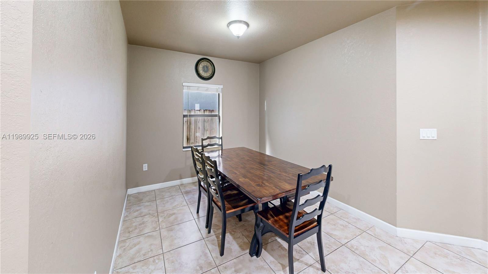 A dining room features a wooden table, four chairs, tiled floors, and a small window — 729 SE 34th Ave, Homestead FL 33033, HOMESTEAD, FL