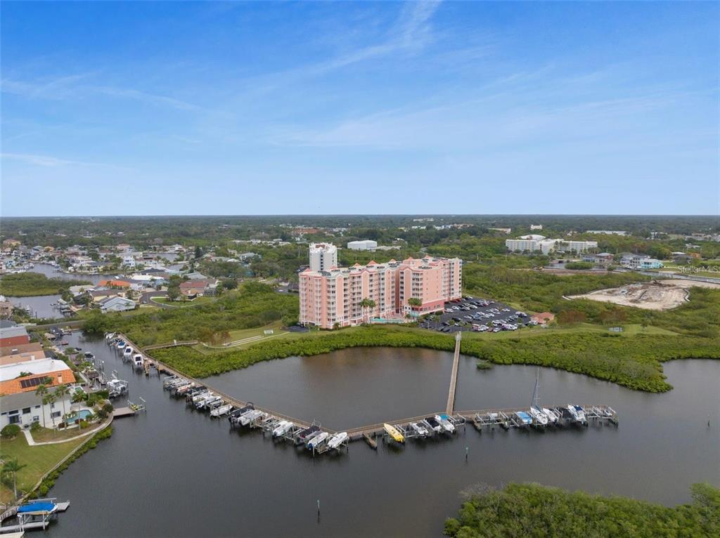 An aerial view shows a large pink residential building next to a boat-filled marina — 4516 SEAGULL DRIVE UNIT 614, NEW PORT RICHEY, FL